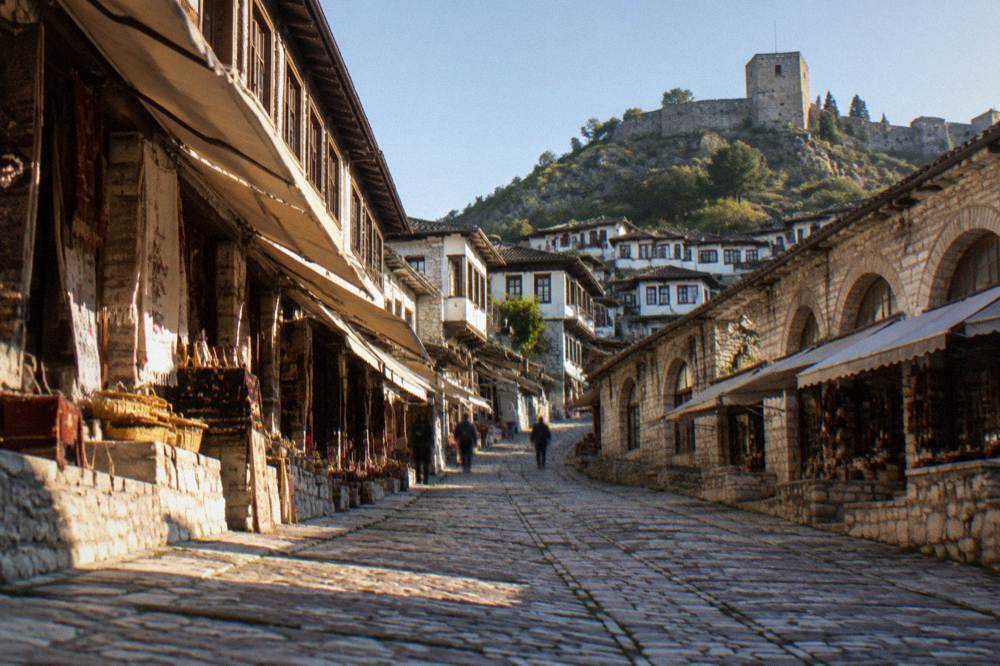 Row of stone houses with wooden-framed windows above a cobbled street in the old town of Berat