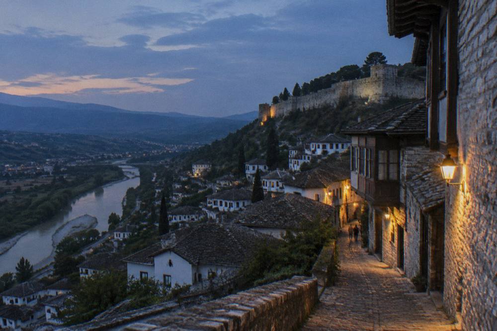 Evening light on the stone facades and shopfronts of a narrow Berat street