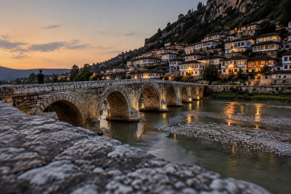 Gorica Bridge crossing the Osum River at dusk with the lit windows of old houses