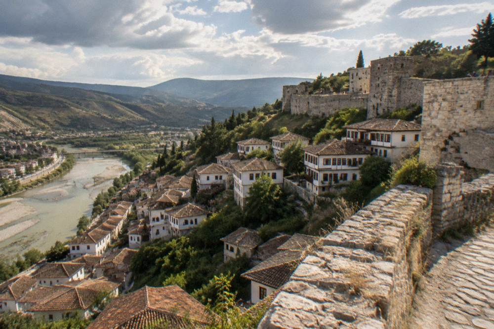 White Ottoman houses stacked on a hillside above a river in Berat, Albania