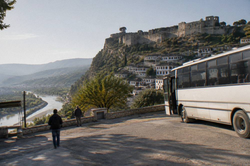 A country bus parked at a small roadside terminal in Albania
