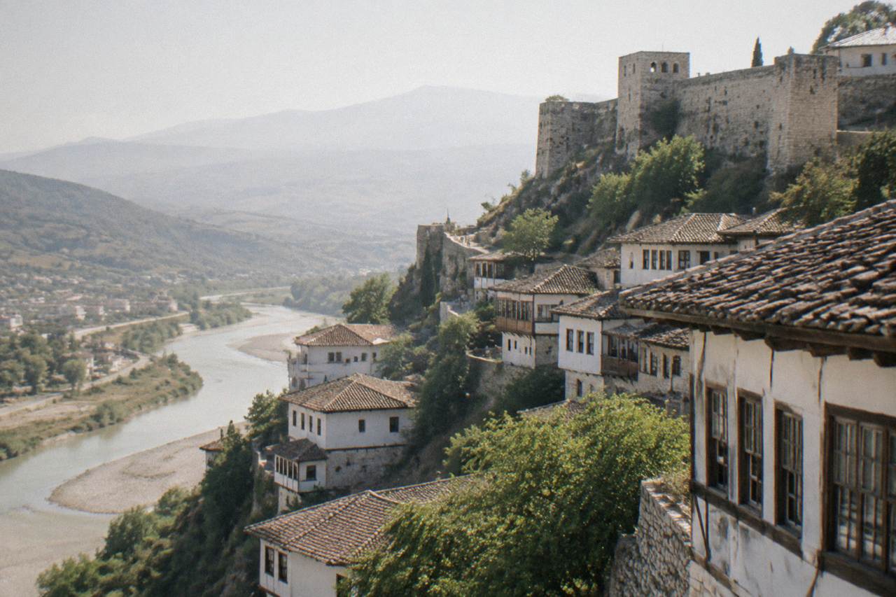 White Ottoman houses stacked on a hillside above a river in Berat, Albania