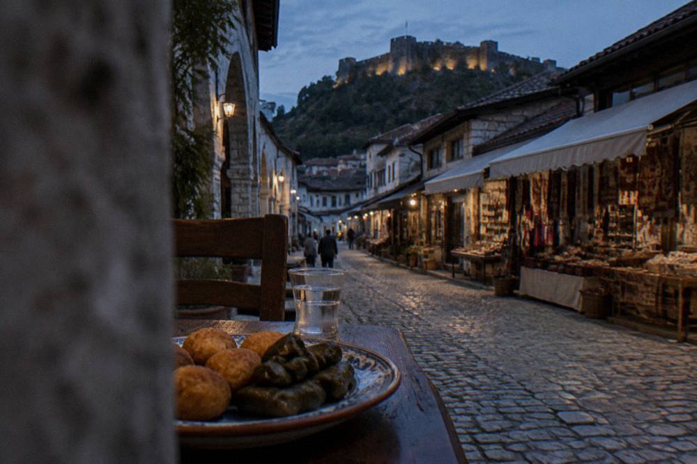 Golden fried rice dumplings and stuffed vine leaves arranged on a ceramic plate beside a glass of raki