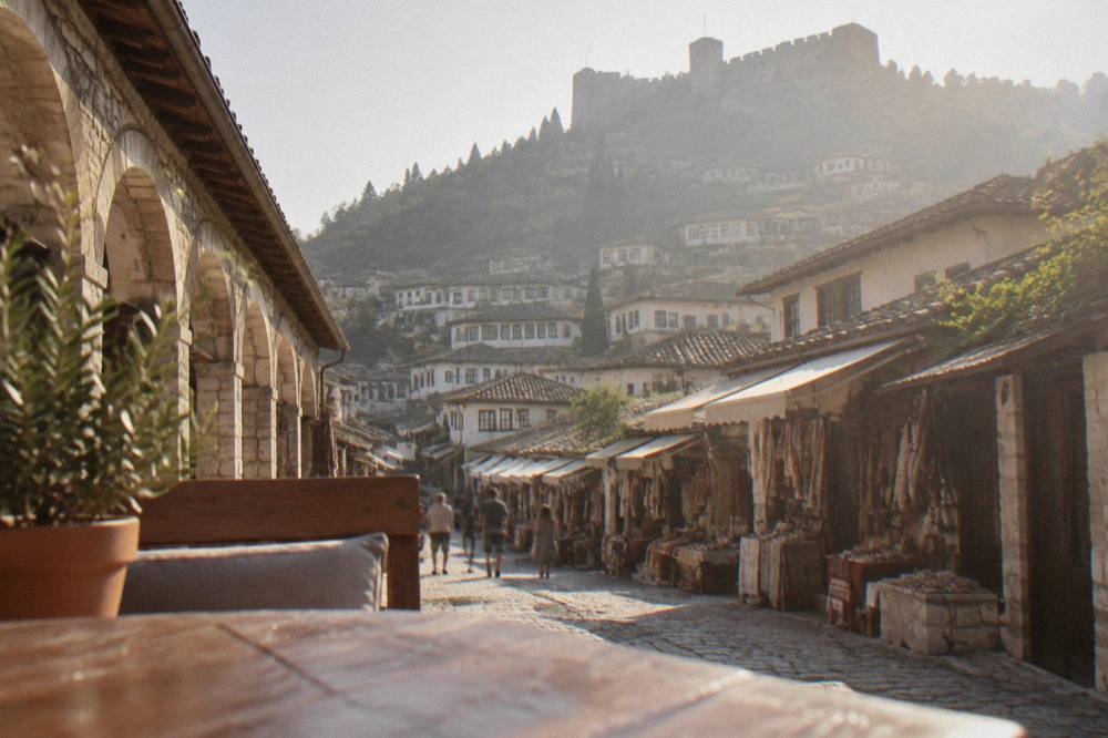 Rooftop terrace at dusk overlooking a hillside of lit Ottoman houses and a castle above