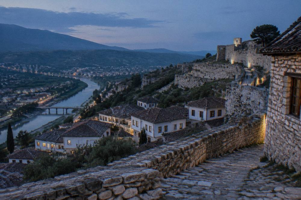 Stone walls and old houses inside Berat Castle overlooking the town below