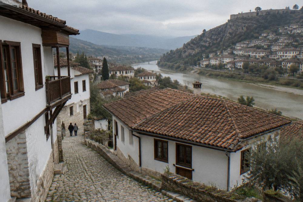 Narrow cobbled lane in Gorica with white houses and the Osum River beyond