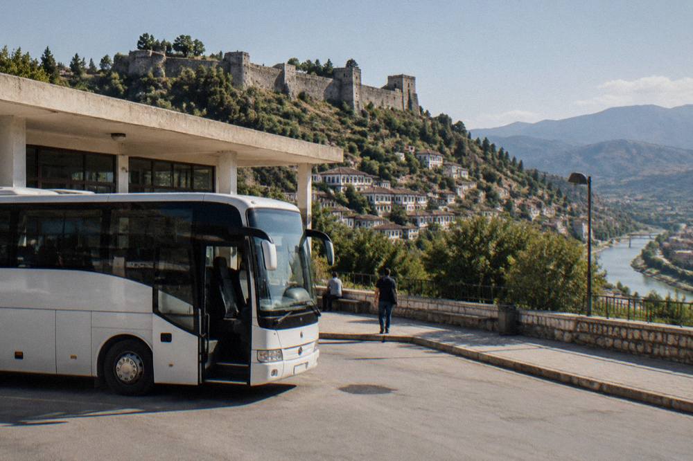 A regional bus parked at a small terminal building on the outskirts of an Albanian town