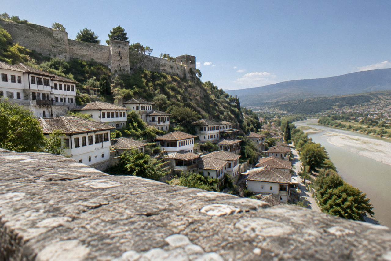 White Ottoman houses stacked on a hillside above a river in Berat, Albania