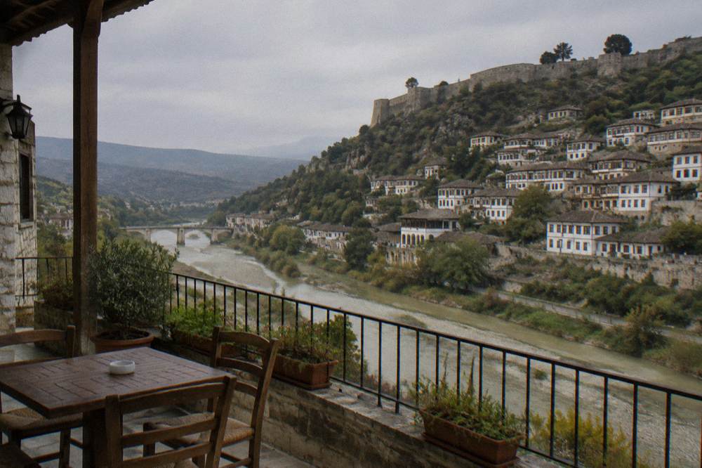 A guesthouse terrace overlooking a river and a hillside of white Ottoman houses.