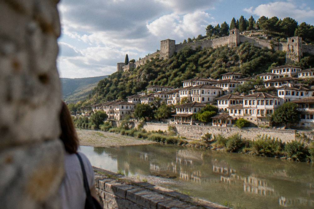 A calm river reflecting a hillside of white houses in soft morning light.