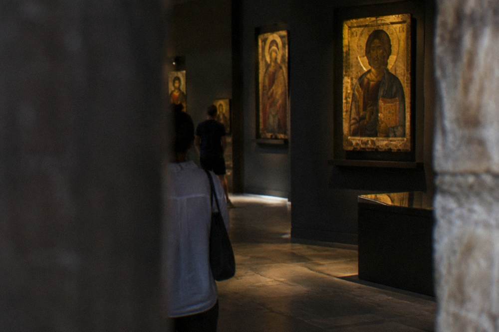 Dim museum interior with gilded Byzantine icons displayed on dark walls