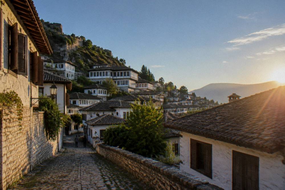 Cobbled lane in Mangalem lined with white Ottoman houses and wooden shuttered windows