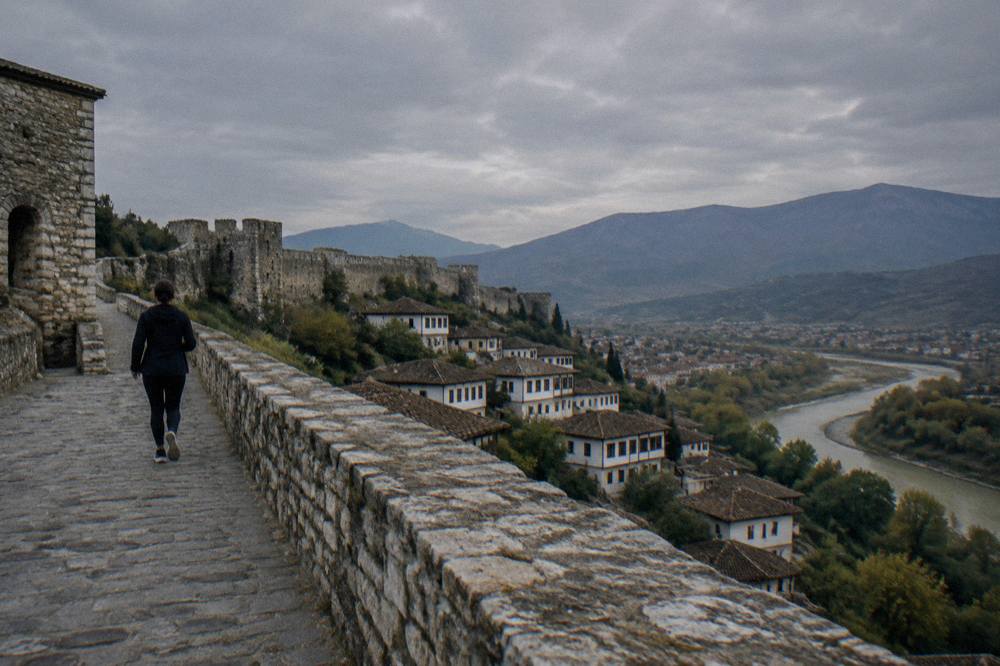 Rooftop view over a stone fortress wall with mountains in the distance