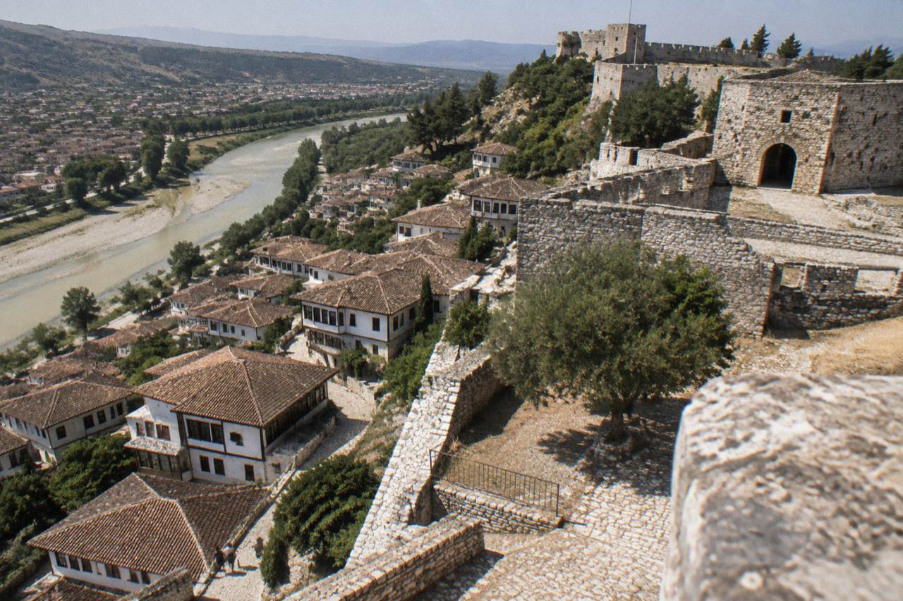 White Ottoman houses stacked on a hillside above a river in Berat